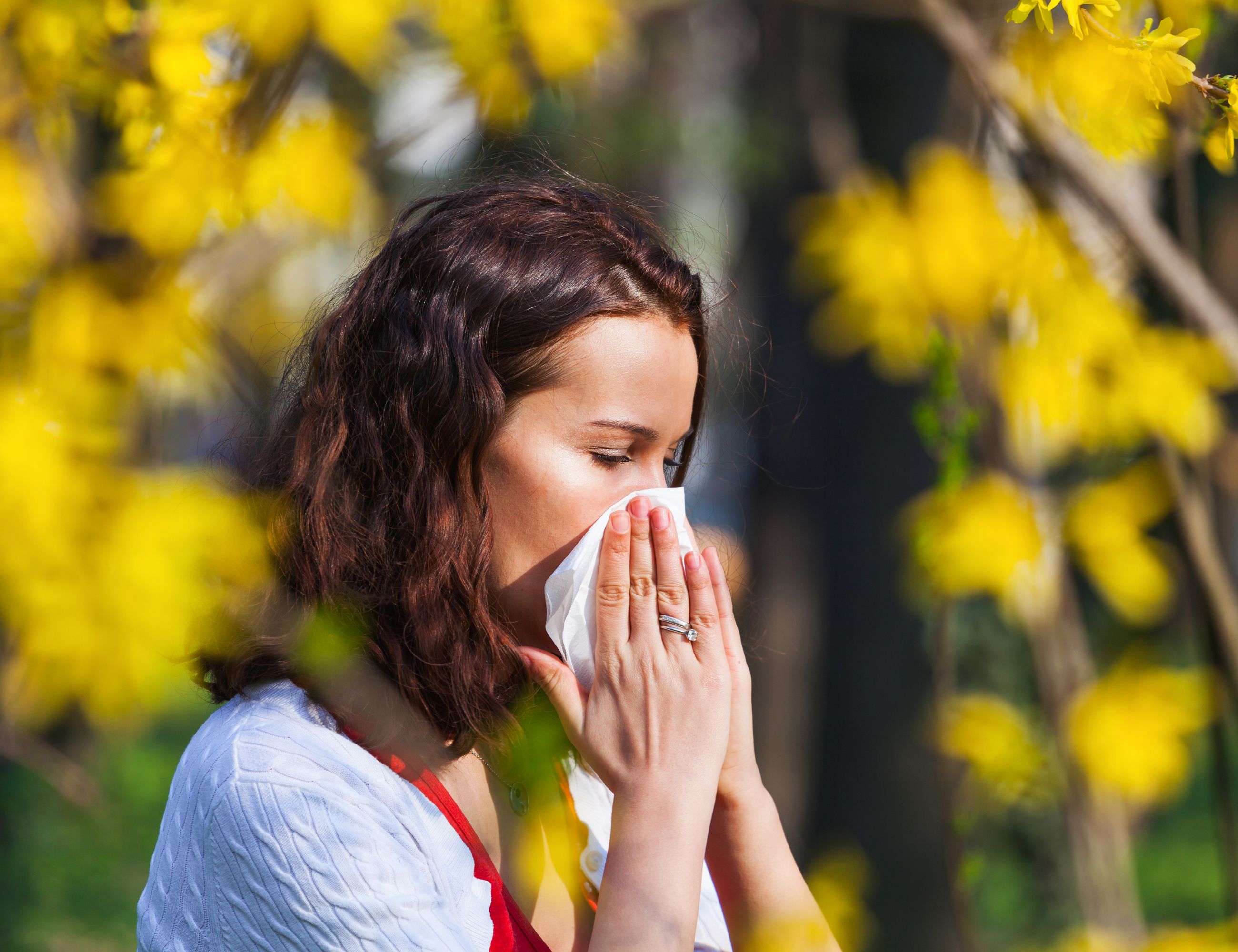 a woman sneezing she is surrounded by yellow flowers