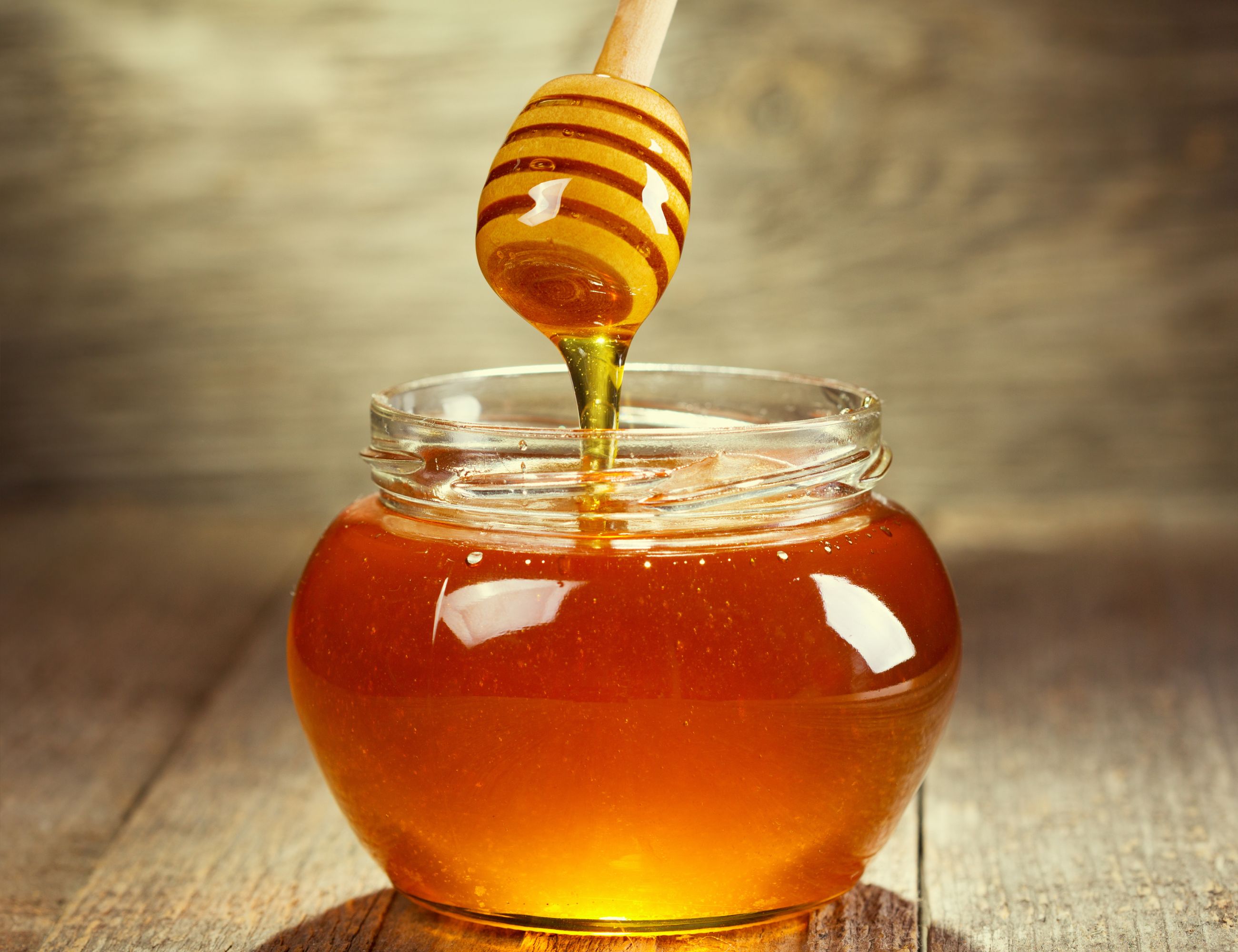 honey in a jar with a stir stick